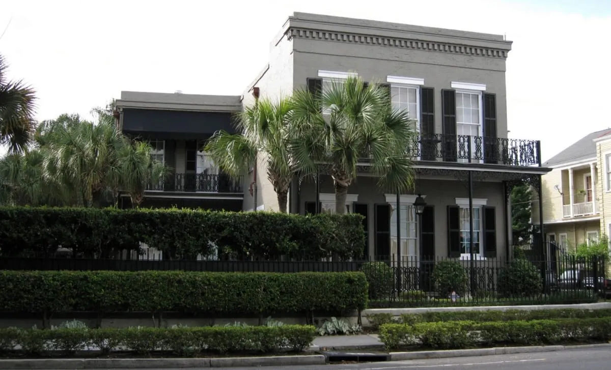 The 19th-century Second Street home with double balconies and lush landscaping, seen from the corner of Magazine Street