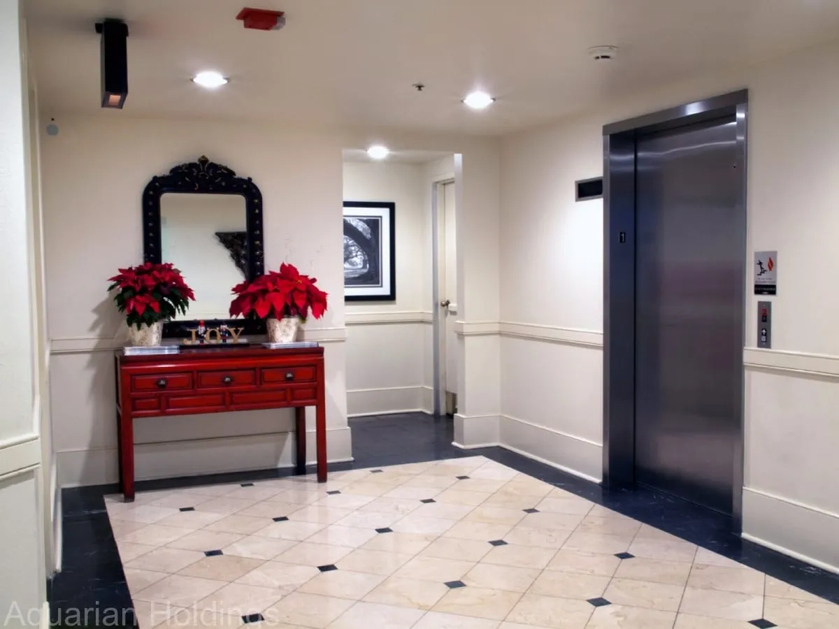 Elevator landing with marble floors and a red console table