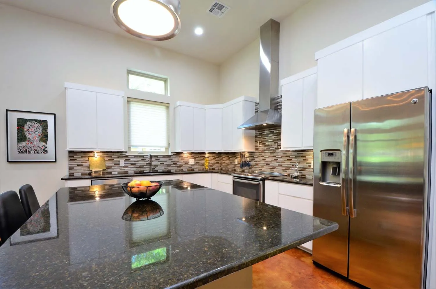 Kitchen island with stainless refrigerator and pendant lighting