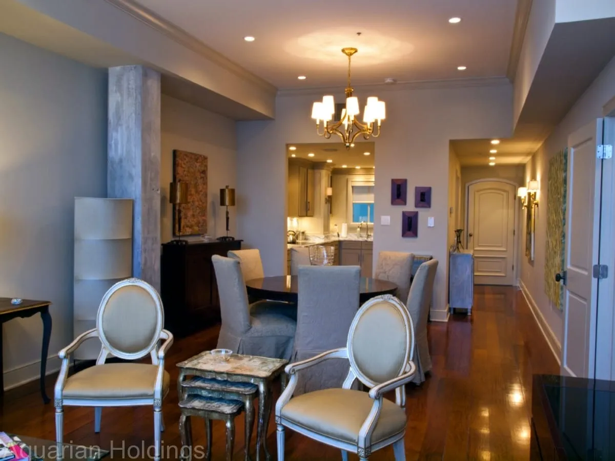 Dining area with chandelier and upholstered chairs, looking down the hall