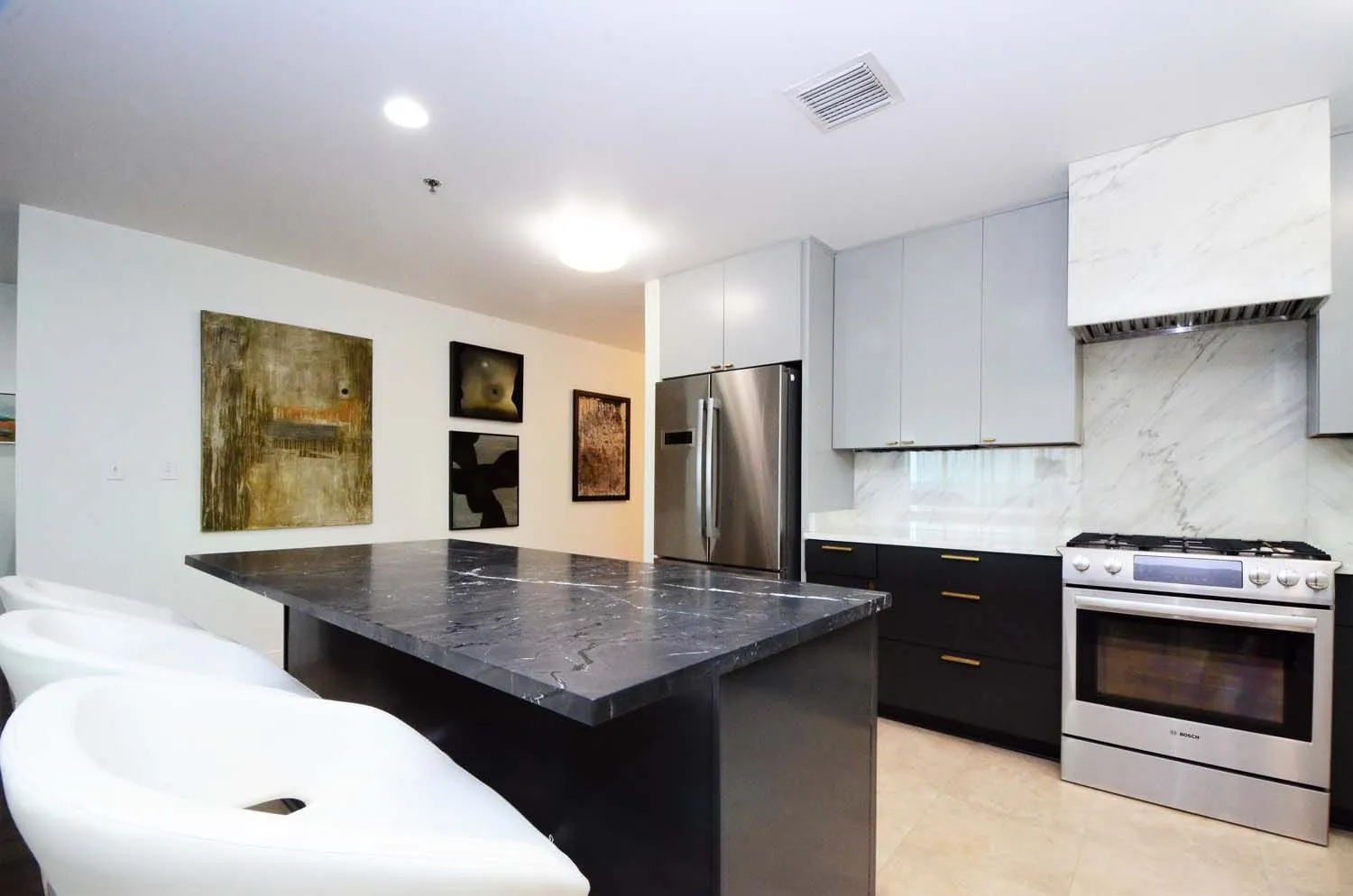 Kitchen with dark island, marble backsplash and stainless appliances