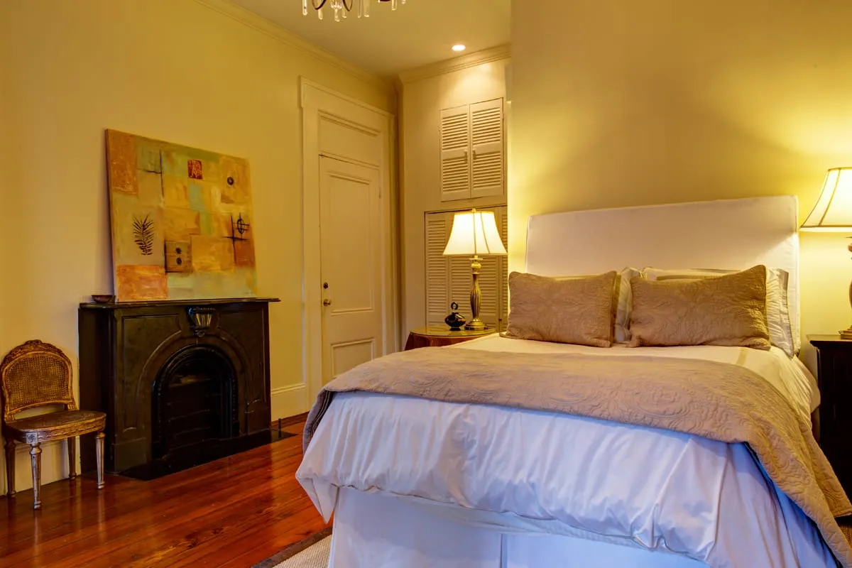 Queen bedroom with original fireplace, lamp and artwork
