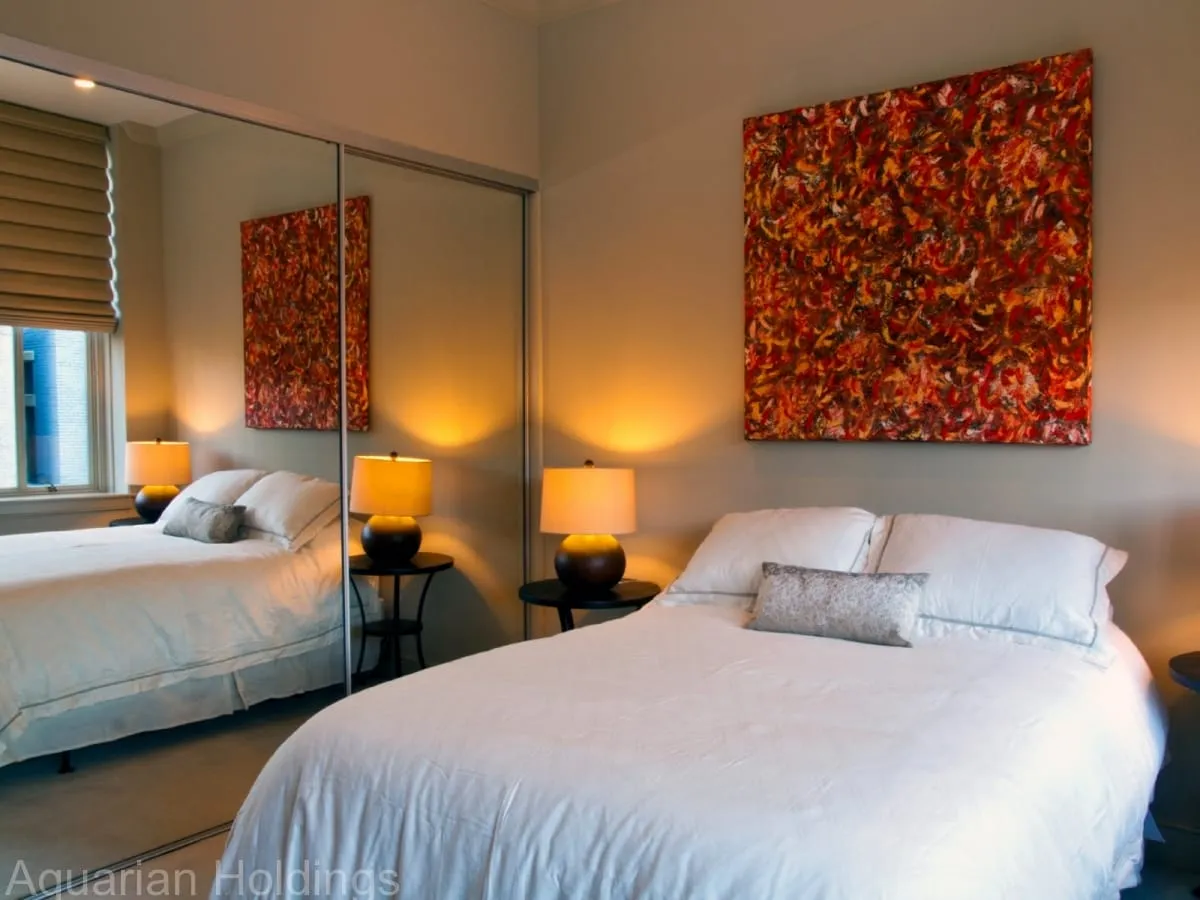 Bedroom with mirrored closet doors and original red artwork