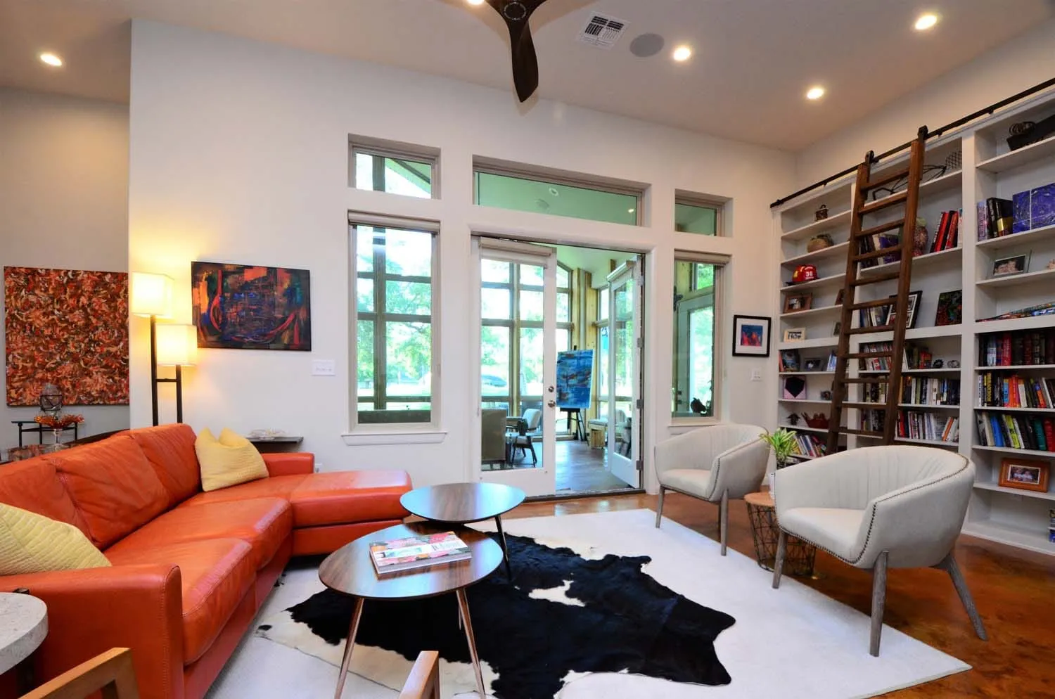 Sitting area with orange sofa, library wall and original art