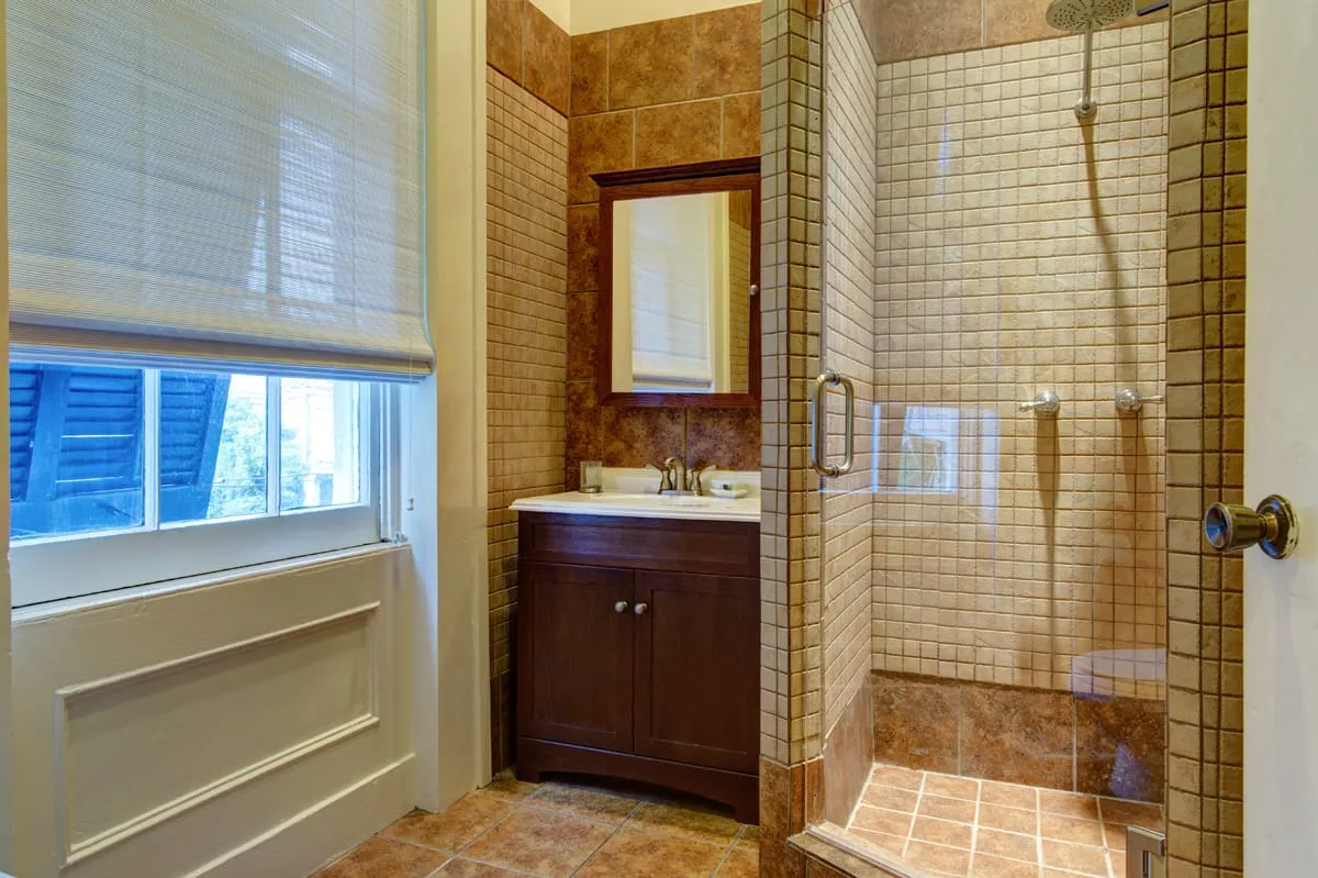Tiled bathroom with glass walk-in shower and wood vanity