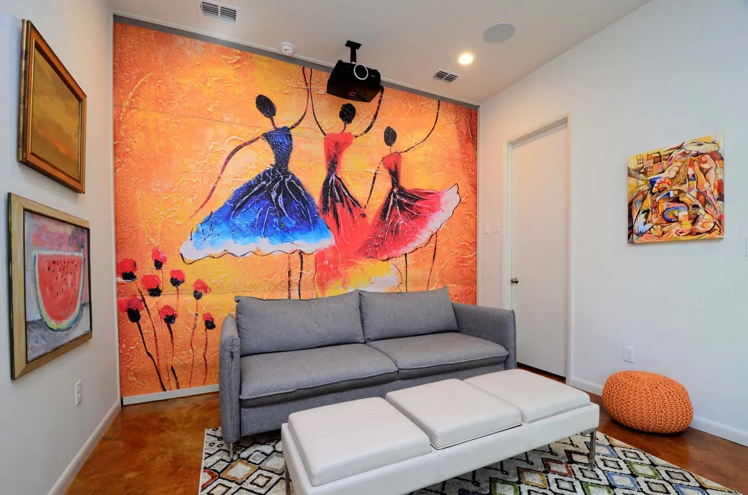 Original mural of dancers above a gray sitting area at Kaiki Circle