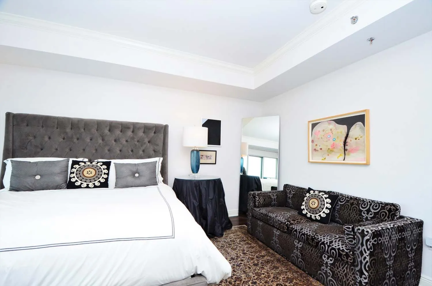 Bedroom with black upholstered bed and patterned sofa