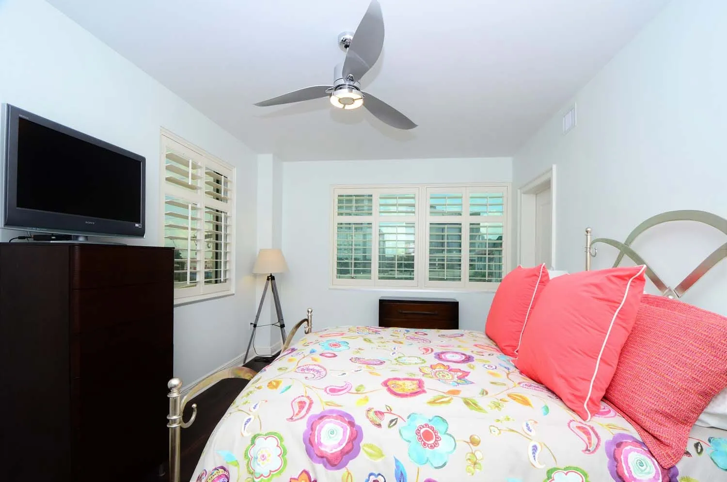 Bedroom with wall-mounted TV and colorful quilt